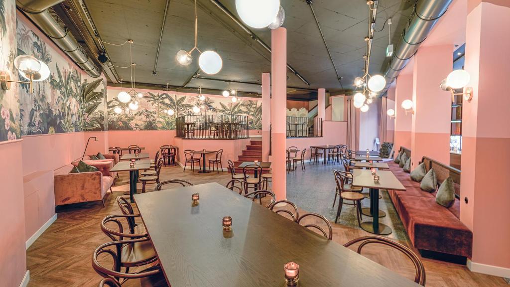 a restaurant with tables and chairs and pink walls at Hotel Sonne in Füssen