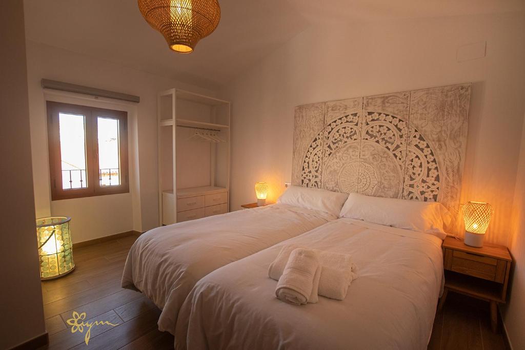 a bedroom with a white bed with two towels on it at Apartamentos Turísticos AbrilyMarzo in Cáceres