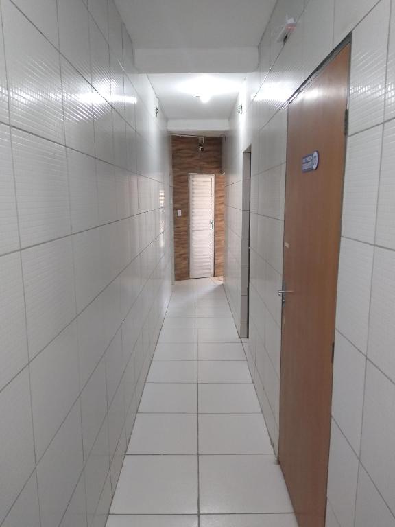 a hallway with white tiled walls and a door at HOTEL CIDADE EXPRESS 24H in Teresina