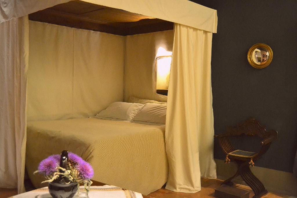 um quarto com uma cama de dossel e uma cadeira em Sanpolo 1544 Antique Room em Urbino