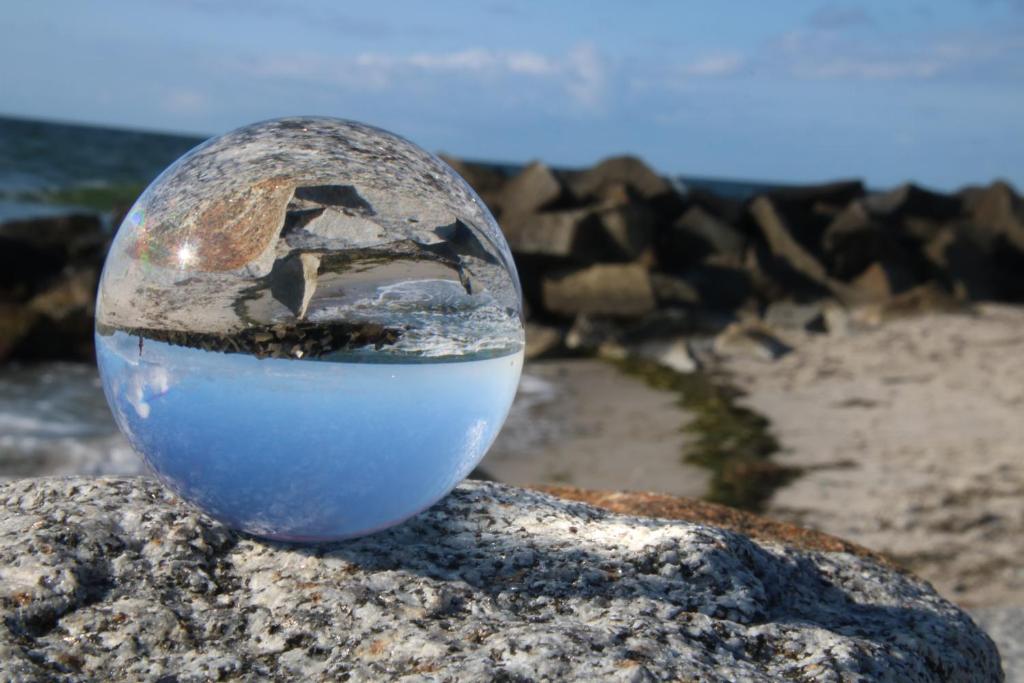 a glass ball sitting on a rock on the beach at Ferienwohnung Boddenkieker bis 4 Personen, Sagard-Neddesitz, 70m2 in Sagard