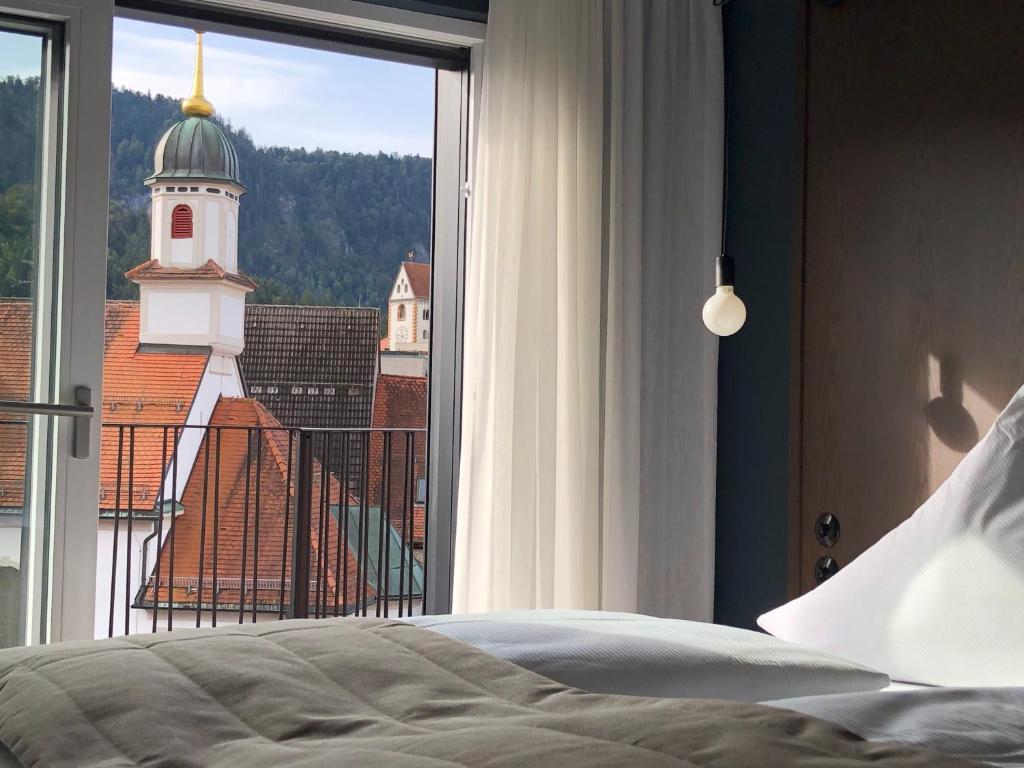 a bedroom with a bed and a window with a clock tower at Hotel Sonne in Füssen