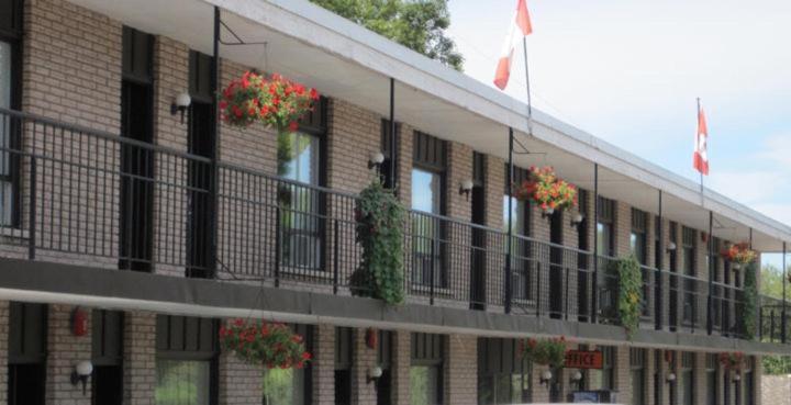 a building with potted plants and flags on a balcony at Bancroft Inn & Suites in Bancroft