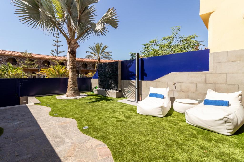 un cortile con erba verde e cuscini bianchi di Bahia Meloneras a San Bartolomé