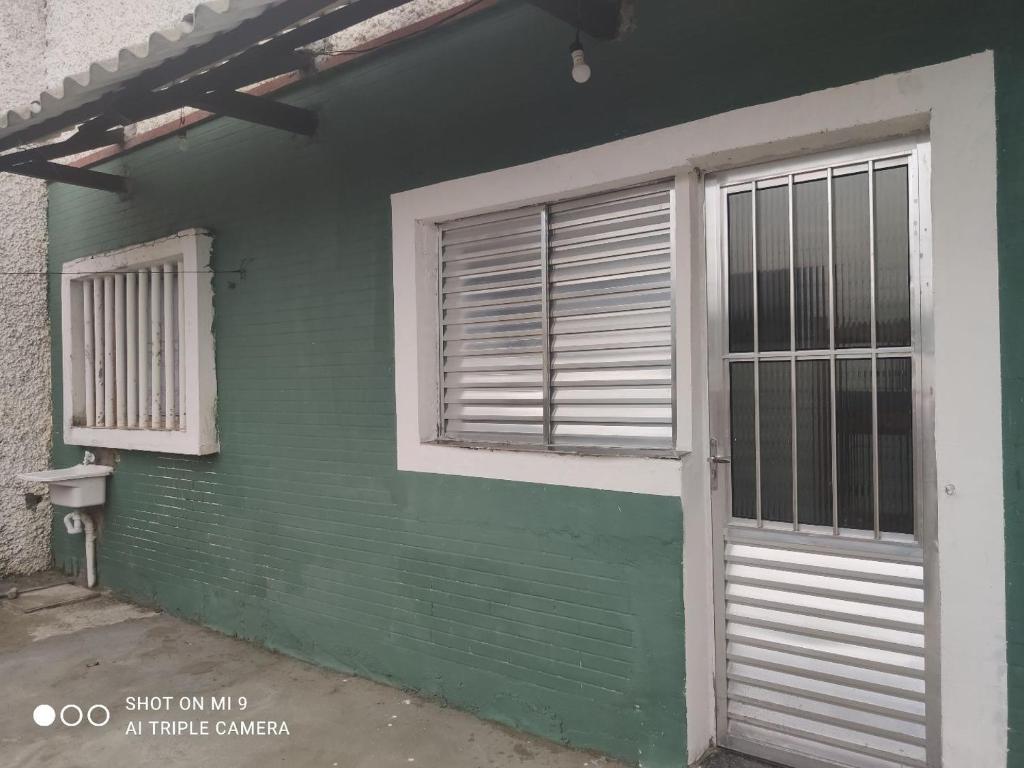 una casa verde con una puerta y una ventana en Recanto, en Mongaguá