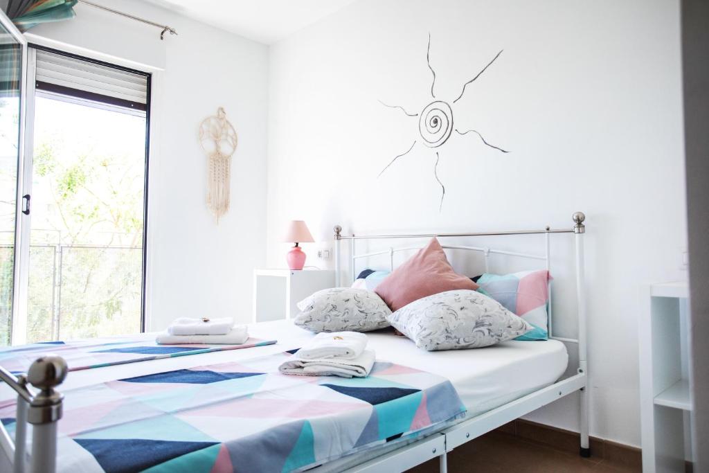 Dormitorio blanco con cama con almohadas coloridas en Corals B&B Apartment, en Denia