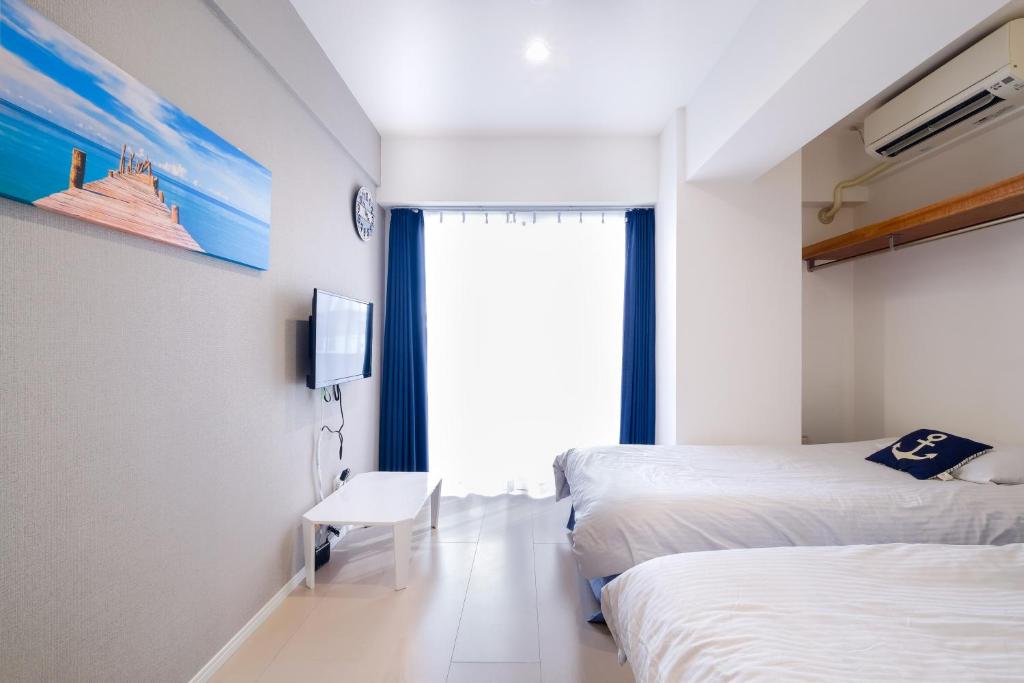 那覇市にあるグッドライフアパートメント那覇のベッド2台と窓が備わるホテルルームです。