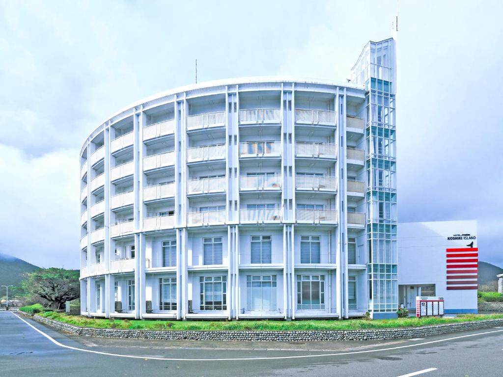 duży biały budynek z drogą przed nim w obiekcie HOTEL AreaOne KoshikiIsland w mieście Satsumasendai