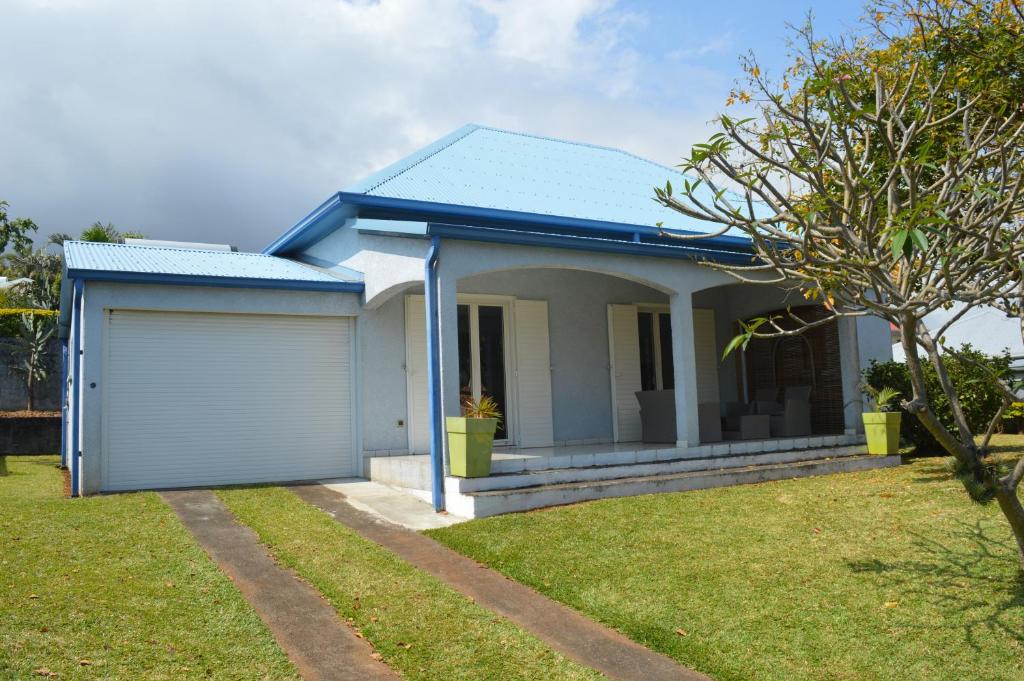 a house with a blue roof and a garage at Location saisonnière Les Hirondelles - Manapany in Saint-Joseph