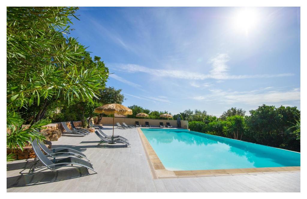 a swimming pool with chairs and an umbrella at Via Mare in Sainte-Lucie de Porto-Vecchio