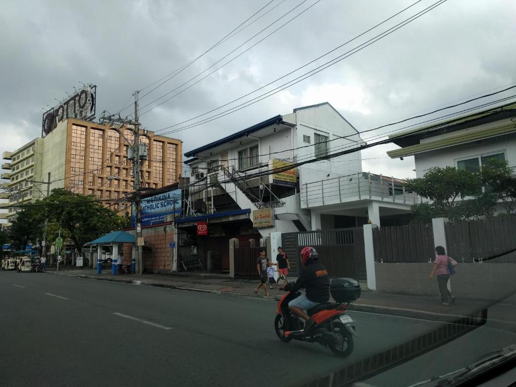 a person riding a motorcycle down a city street at La Trinidad Pension House in Manila