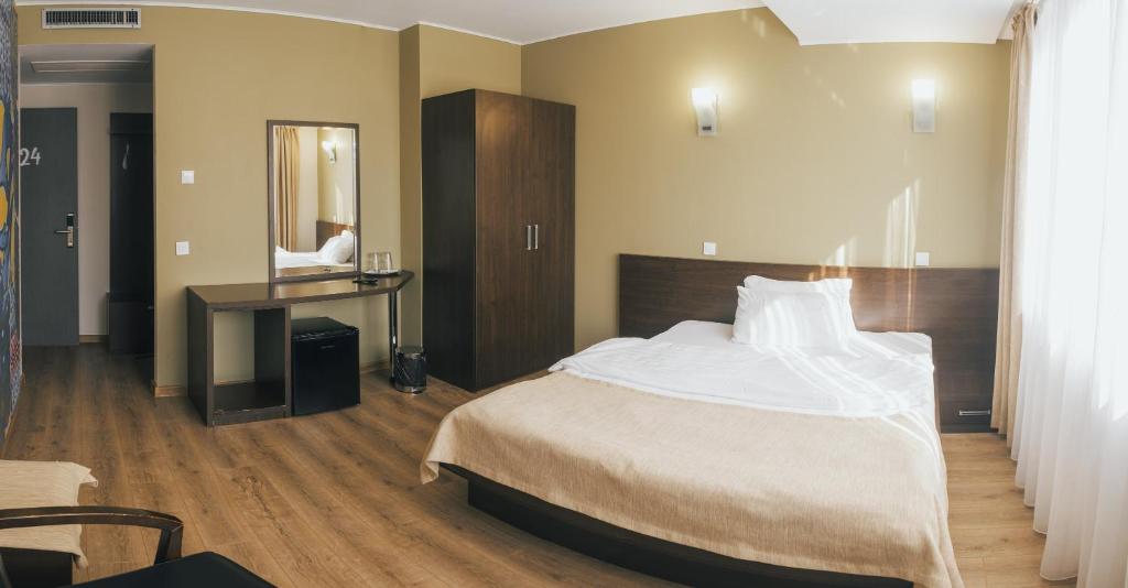 1 dormitorio con cama, escritorio y espejo en Graffiti Hotel, en Bucarest
