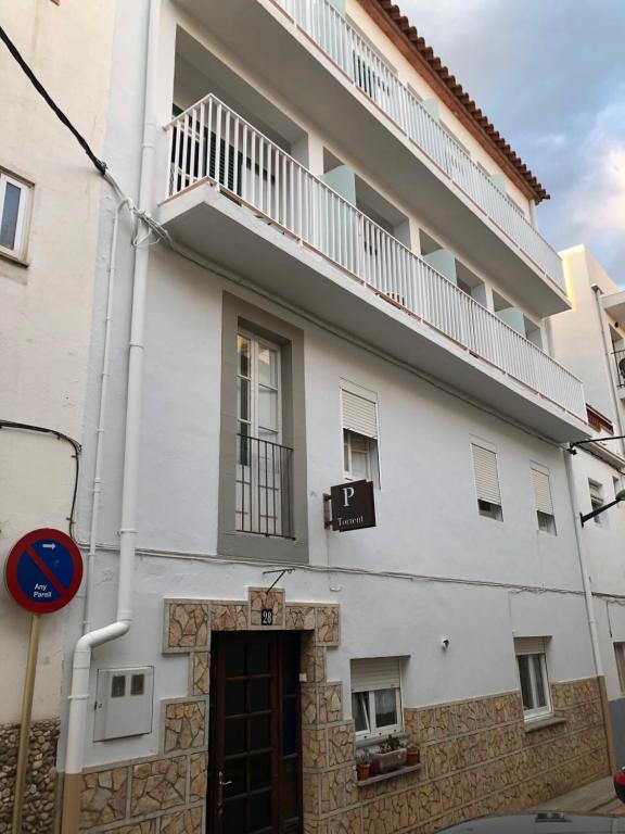a white building with a balcony on top of it at Pensió i Apartament Torrent in L'Escala