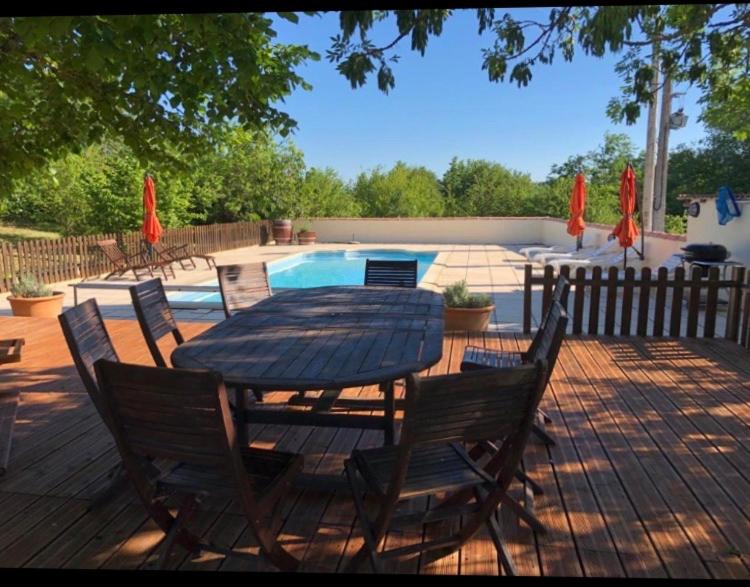 una mesa de madera y sillas con una mesa y una piscina en La Tourouzelle, en Lauraguel