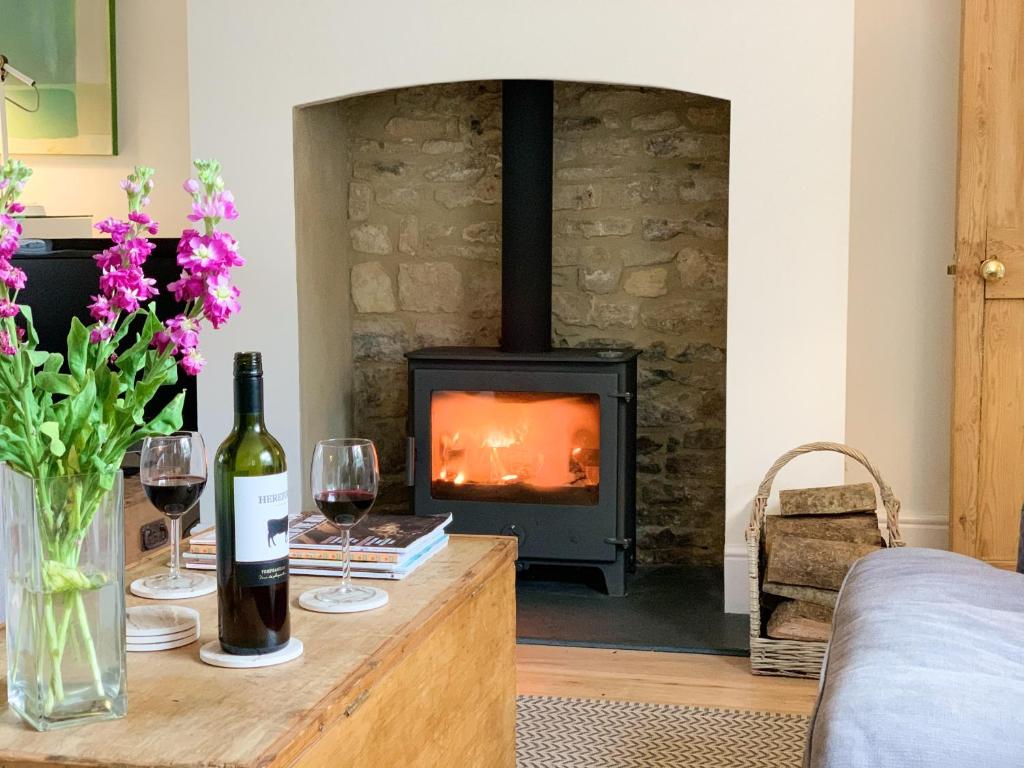 a living room with a fireplace and a table with wine glasses at Jasmine Cottage in Charlbury