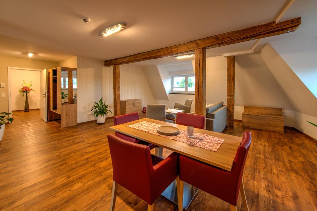 a dining room with a table and red chairs at Heidequartier Harz in Wernigerode