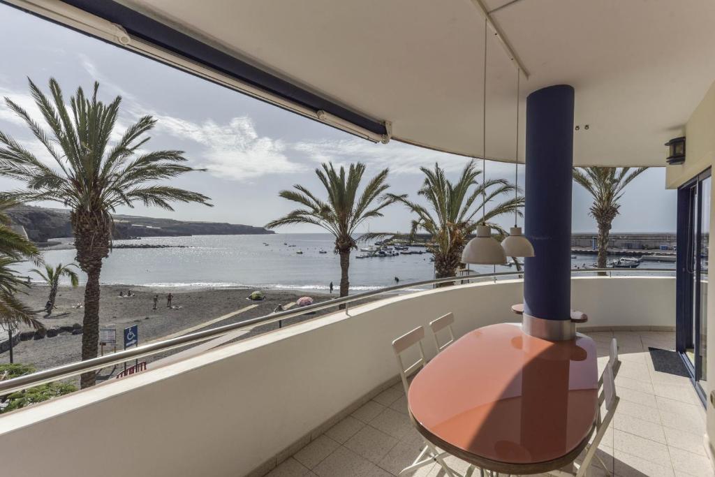 a balcony with a view of a beach and palm trees at Merlín 1-1 in Playa de San Juan