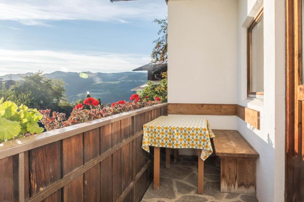 una mesa y un banco en un balcón con vistas en App Peterbühl - Gasser en Vols am Schlern