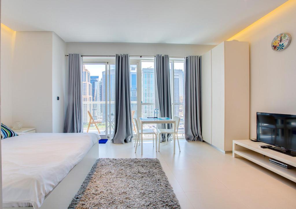 a bedroom with a bed and a tv and a table at Stylish Studio in West Avenue Dubai Marina in Dubai