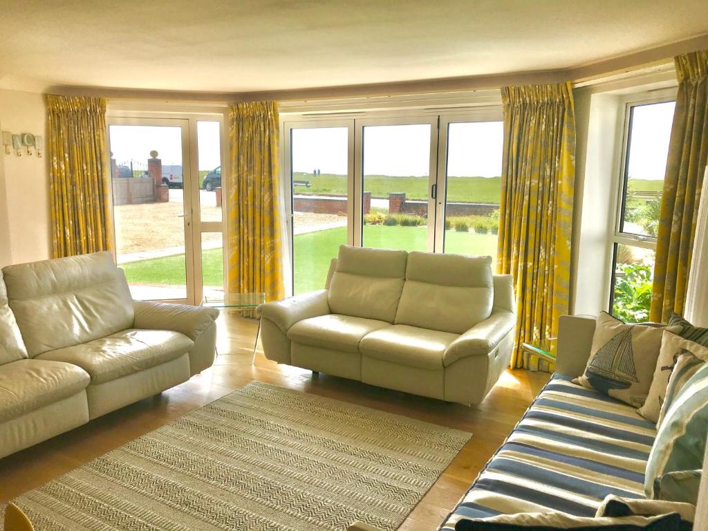 a living room with a couch and chairs and windows at Barton on Sea self contained, stunning sea views in Barton on Sea