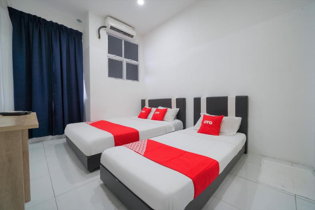 two beds with red pillows in a room at OYO 89820 Sp Berlian Inn in Sungai Petani