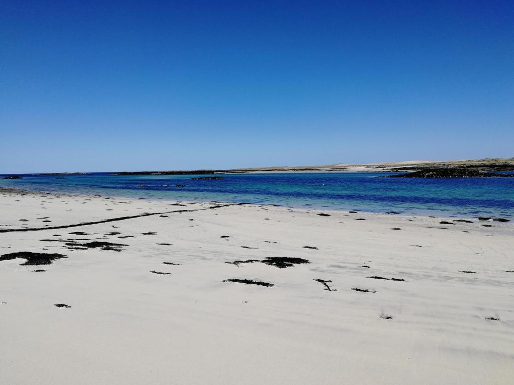 a beach with footprints in the sand and water at The Fisherman's Snug North Uist in Paible