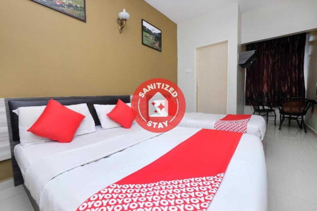 Duas camas num quarto com almofadas vermelhas e brancas em Super OYO 1152 Heaven Hill 2 em Cameron Highlands