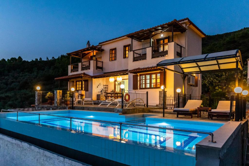 a house with a swimming pool in front of a house at Villa Peparethos in Stafylos