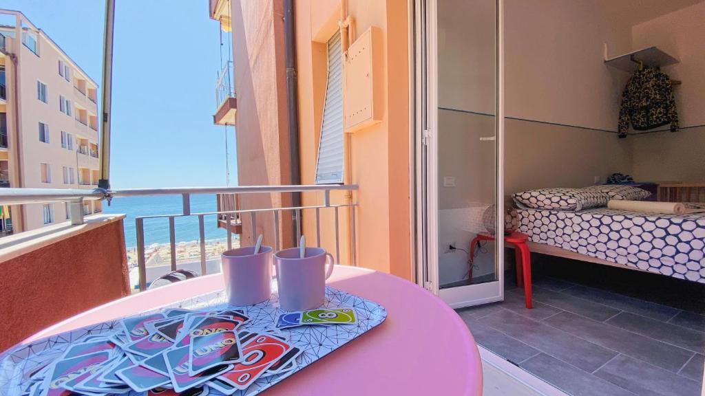 balkon z różowym stołem i łóżkiem w obiekcie Babyaccommodation Family Panoramic II w mieście Pietra Ligure