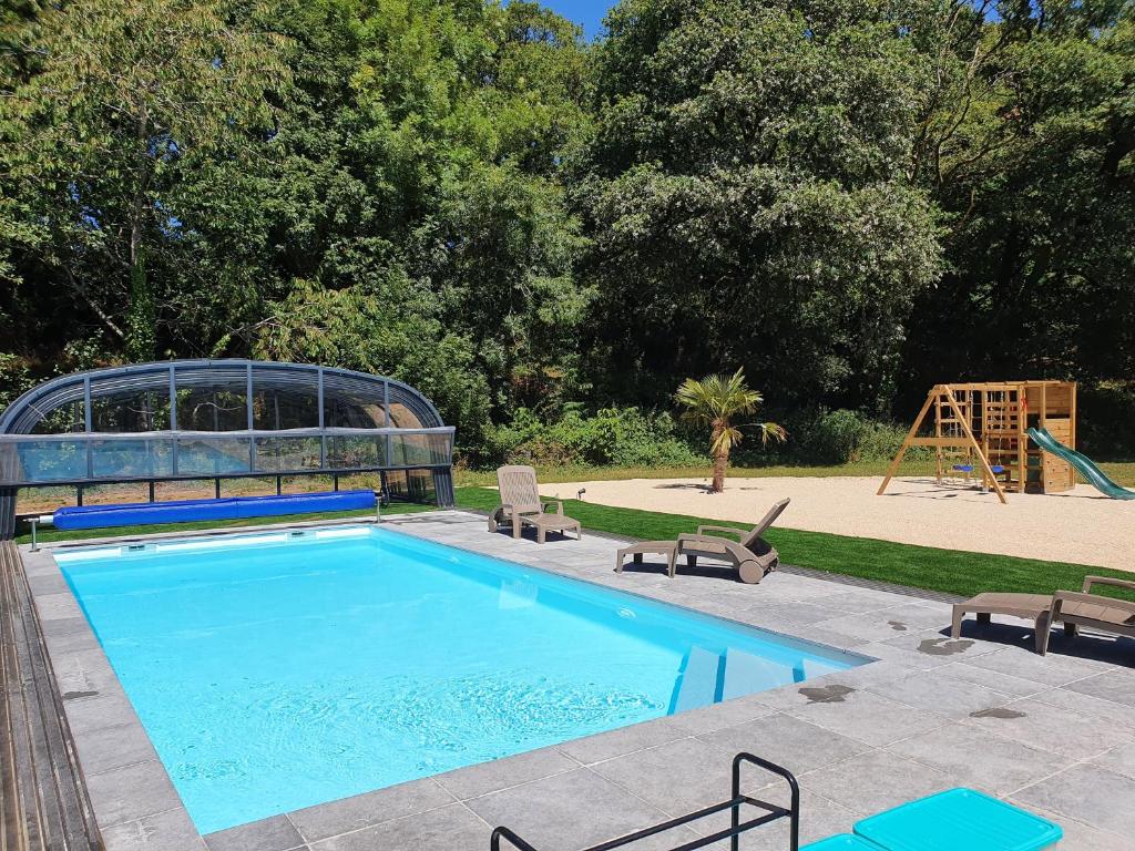 a swimming pool with a slide and a playground at Gîtes de Maner Ster - Le Frêne Piscine ou Le Chêne Piscine et Spa privatif in Cléden-Poher