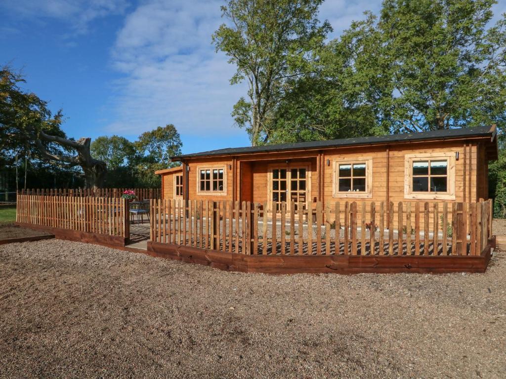 une cabane en rondins avec une clôture en bois dans l'établissement Tythe Lodge, à Sleaford