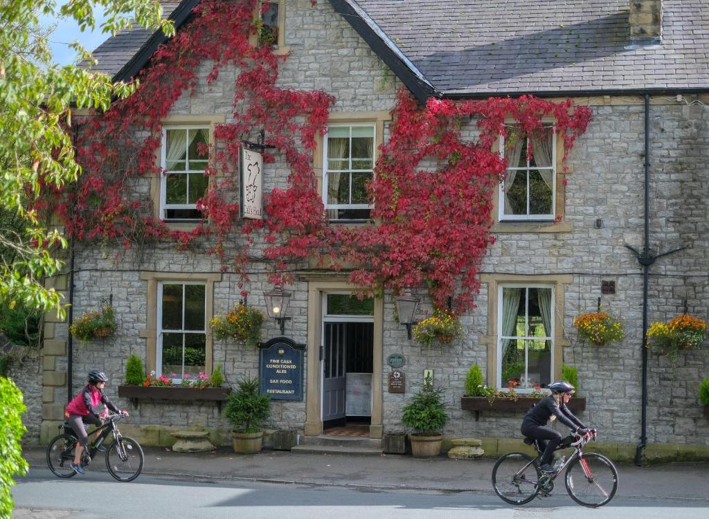Dos personas montando en bicicleta delante de un edificio con flores en Calf's Head Hotel en Clitheroe