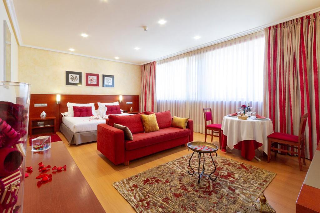 Habitación de hotel con cama y sofá rojo en Hotel MIRAVALLE, en Ourense