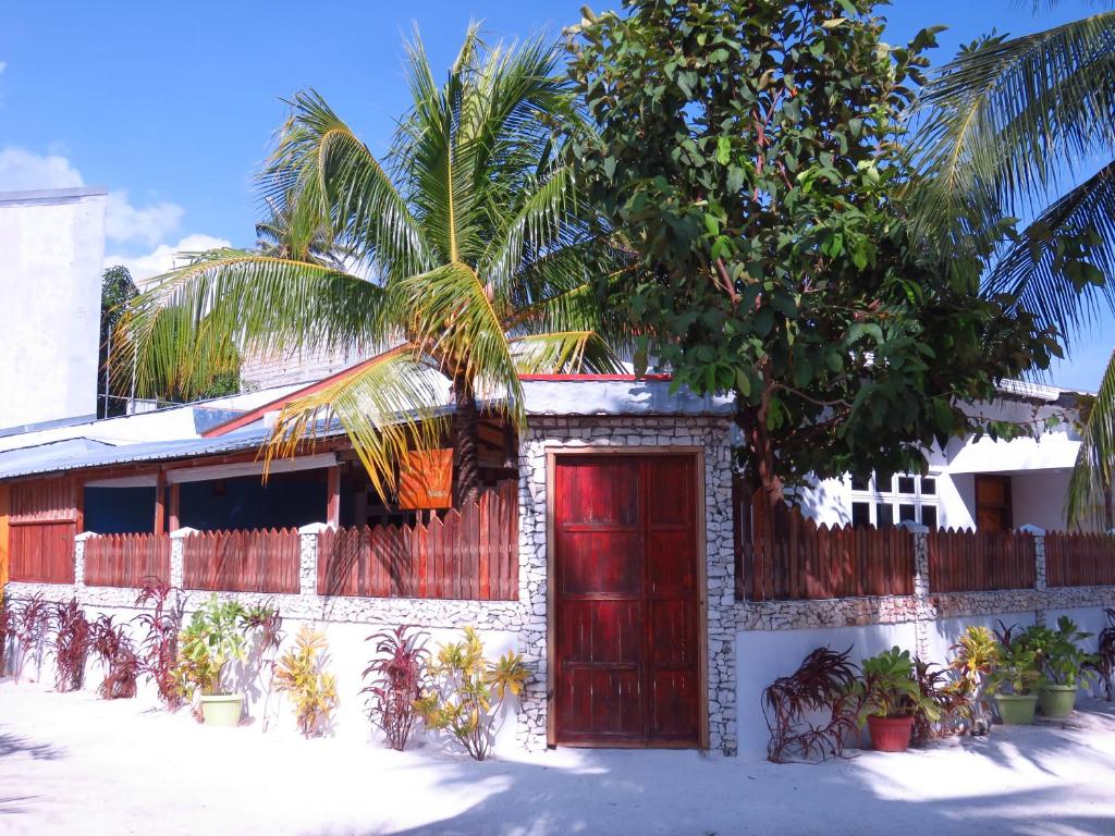 una casa con una puerta roja y una palmera en The Sunrise Huraa, en Huraa