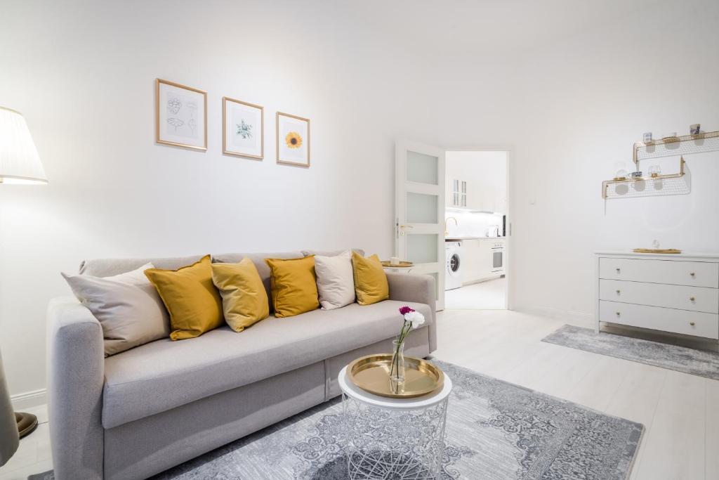 ein Wohnzimmer mit einem grauen Sofa und gelben Kissen in der Unterkunft BpR LYNX Home with A/C in Budapest
