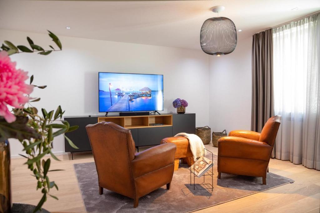 a living room with two chairs and a flat screen tv at MUNICH FINEST APARTMENTS in Munich
