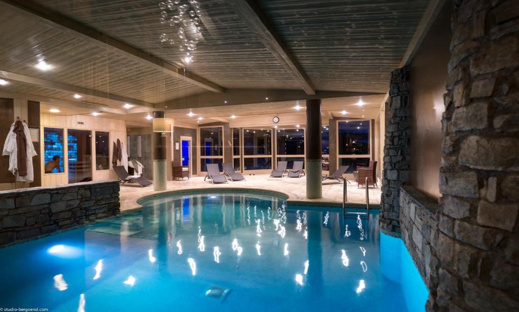 a swimming pool in a hotel with a stone wall at Résidence l'Oxalys in Val Thorens