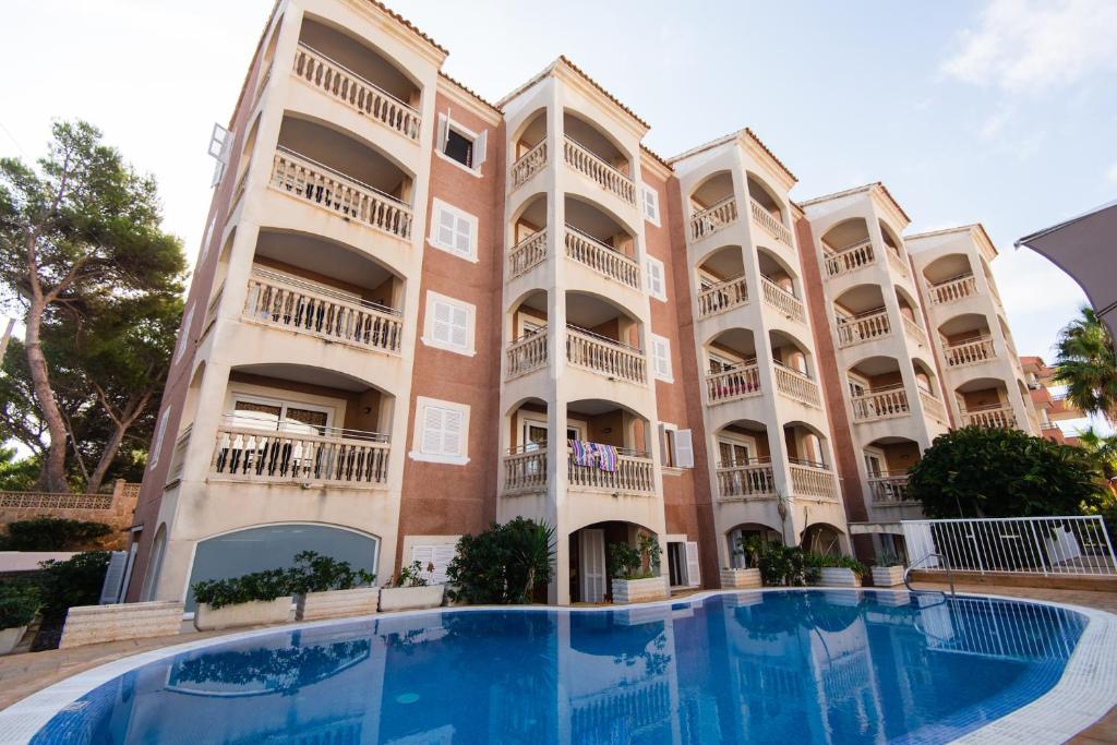 a building with a swimming pool in front of it at Apartamentos Quijote Park in Cala Ratjada