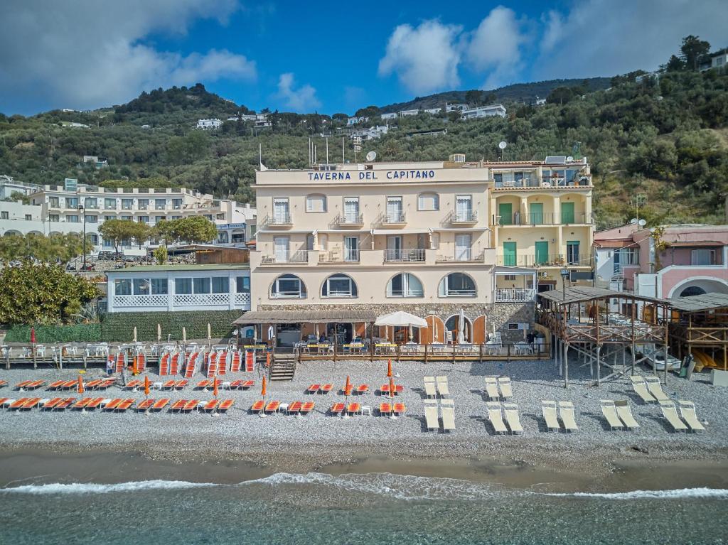 a hotel with chairs and umbrellas on a beach at Taverna Del Capitano in Massa Lubrense