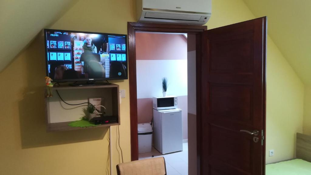 Pokój z telewizorem na ścianie obok drzwi w obiekcie MA-JA 4 w mieście Bük