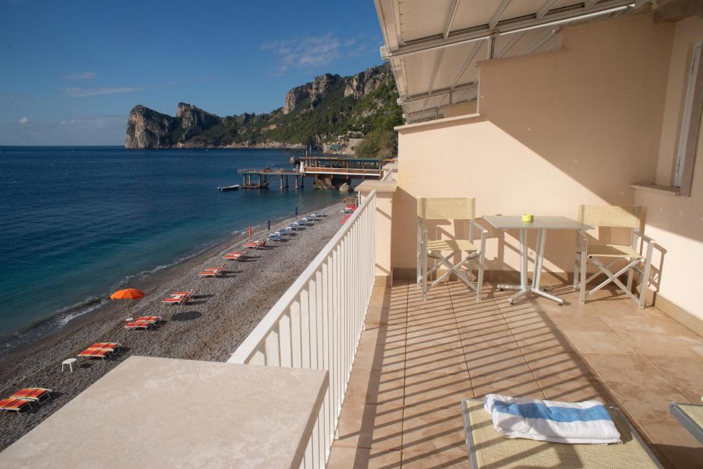 uma varanda com mesa e cadeiras e a praia em Taverna Del Capitano em Massa Lubrense