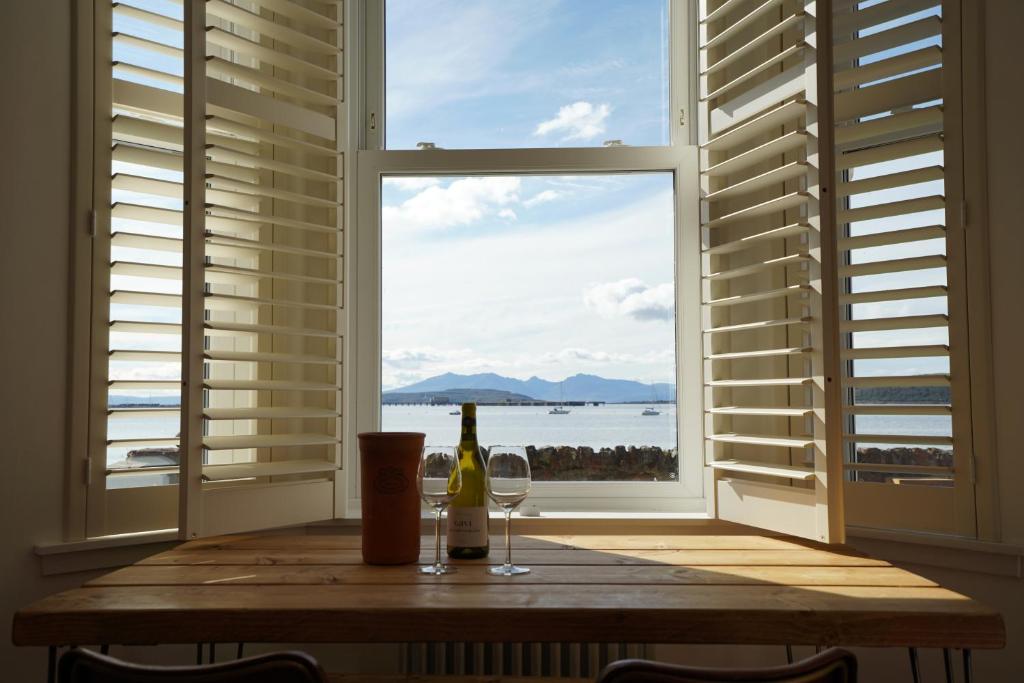 una mesa con una botella de vino y una ventana en Beach house no2 with amazing sea views and private garden onto beach., en Fairlie