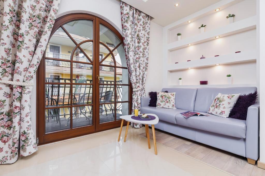 een woonkamer met een bank en een raam bij Apartament Neapol Rezydencja Sienkiewicza by Renters in Zakopane
