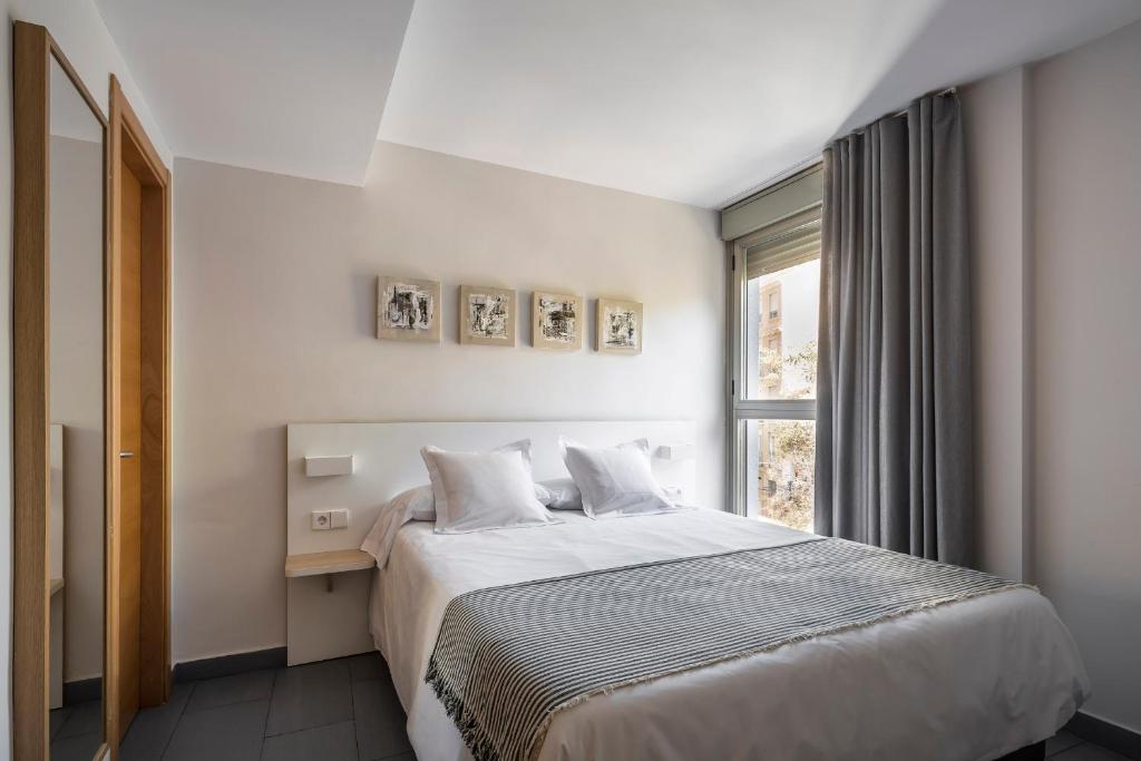 a white bedroom with a bed and a window at Mon Suites Carmen in Valencia