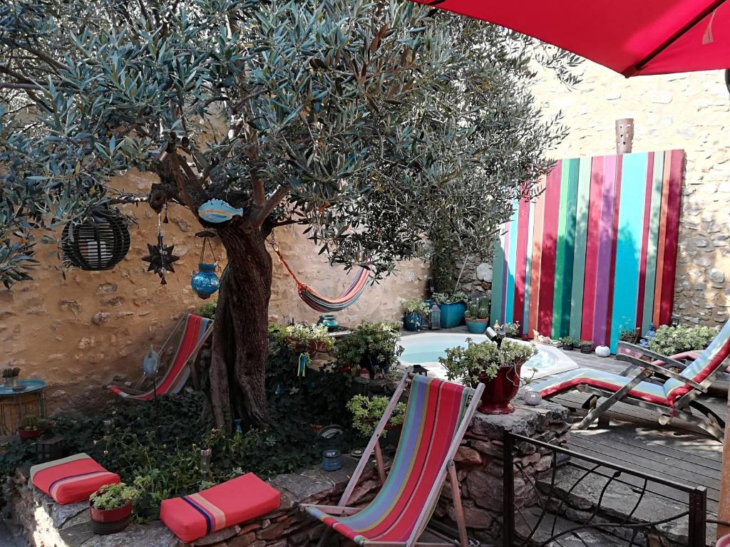 een groep stoelen en een boom en een paraplu bij Maison d'hôte la Tourette in Cucugnan