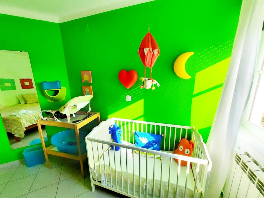 Habitación verde con cuna en un dormitorio en Baby Boom - Duna Parque Group, en Vila Nova de Milfontes