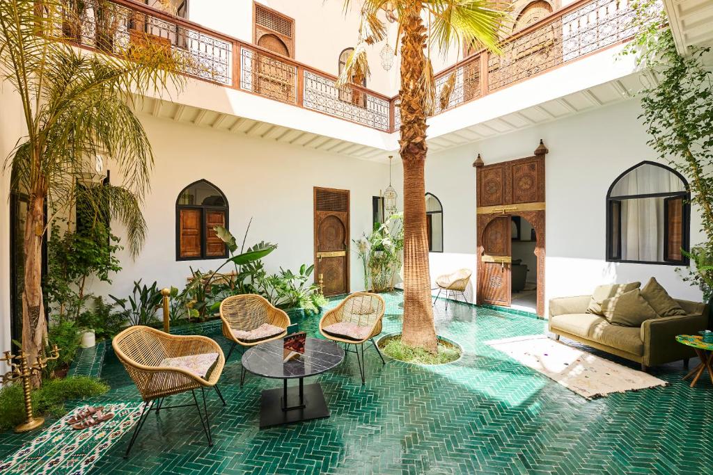 a living room with palm trees and chairs at Riad Dar Yasaman in Marrakesh