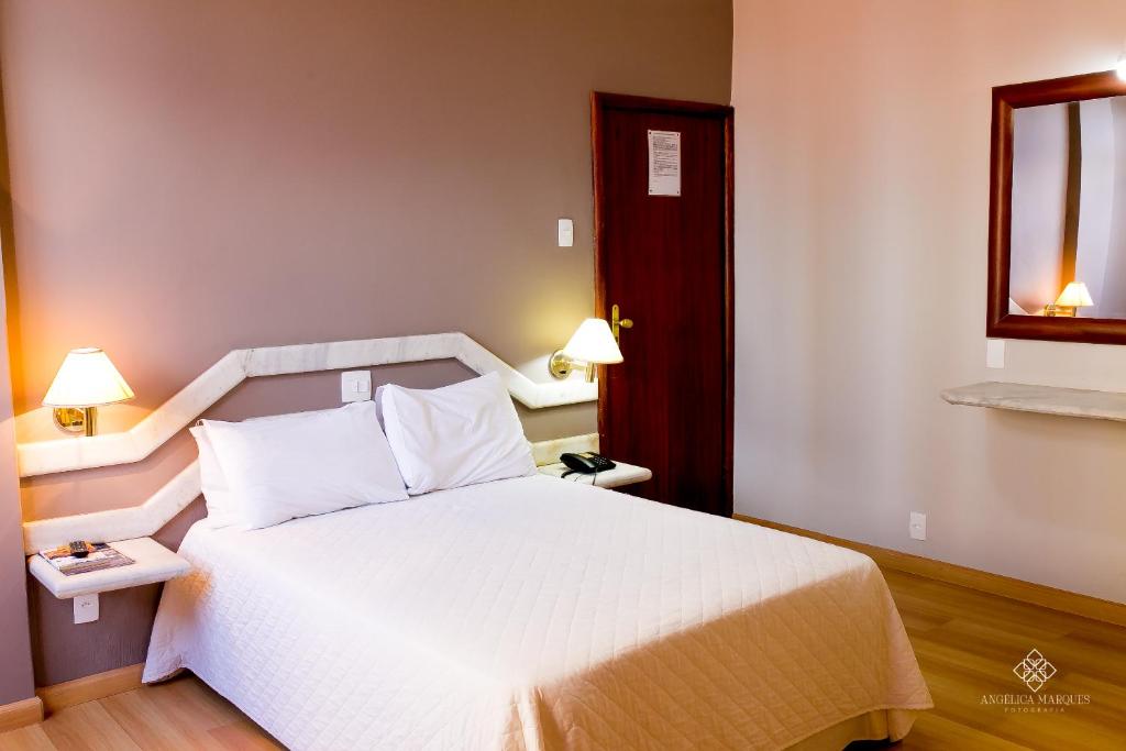 - une chambre avec un lit blanc et une fenêtre dans l'établissement Fenicia Palace Hotel, à Varginha