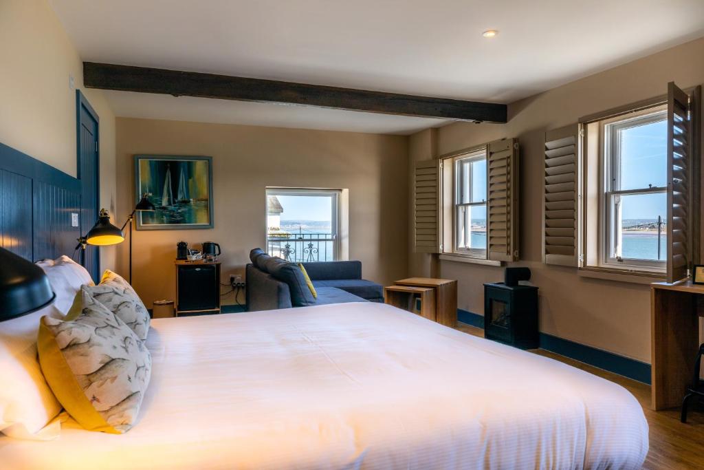 a bedroom with a large white bed and windows at The Seagate in Appledore