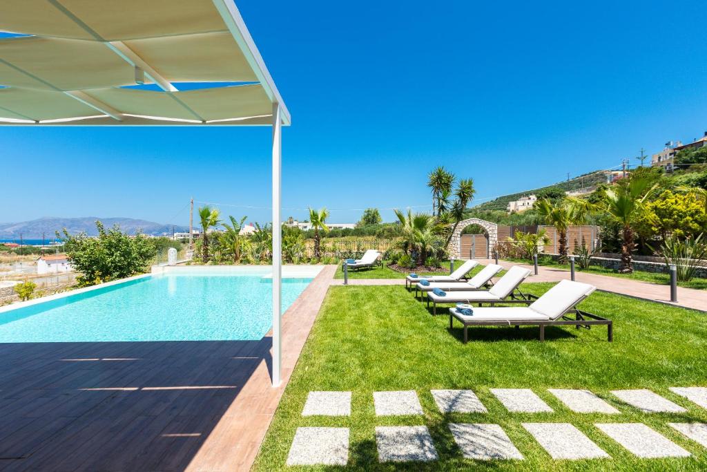 a swimming pool with chaise lounge chairs next to a resort at Villa Anemeli - Luxury pool villa with gorgeous seaview in Kissamos